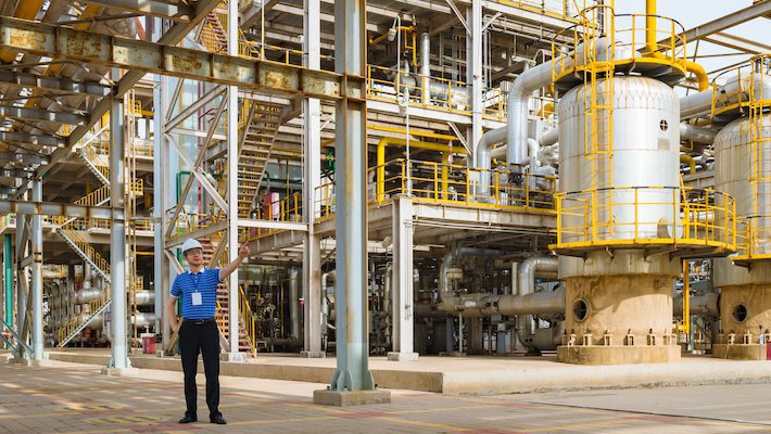 Man standing in front of ASME vessels at a chemical plant