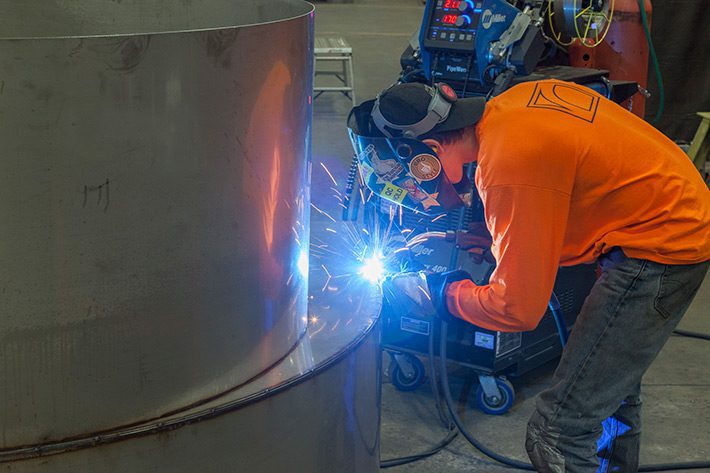 welder placing a weld on industrial equipment