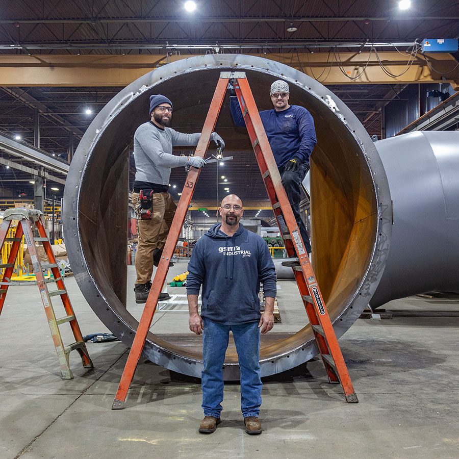 An image of some of the GSM Industrial team standing in front of industrial ductwork