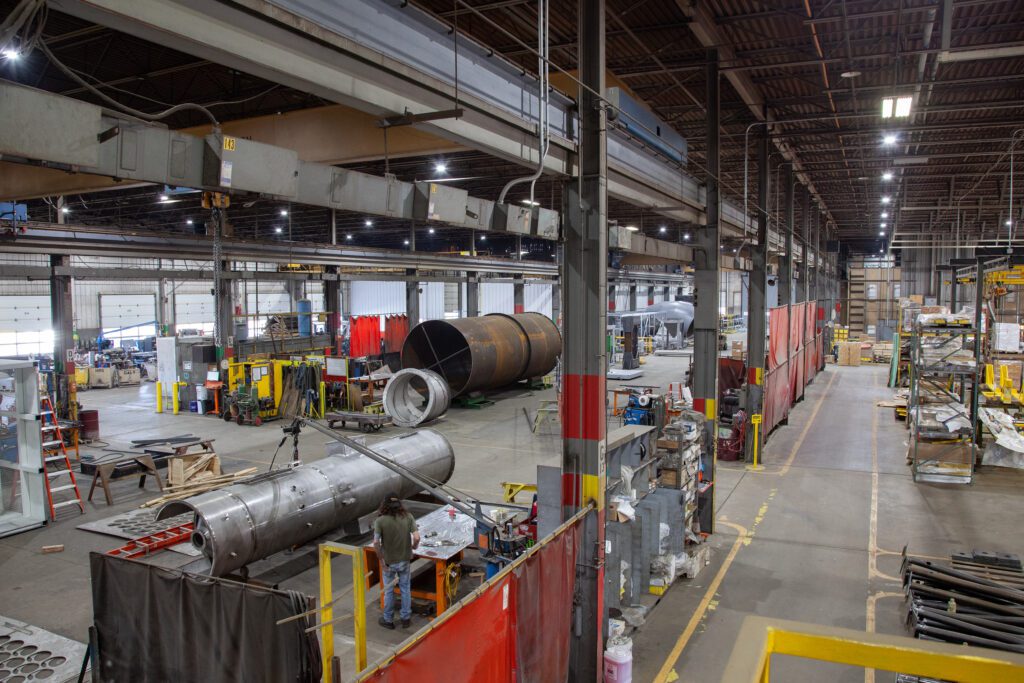 A view of the industrial shop with many metal parts and some equipment in the picture.