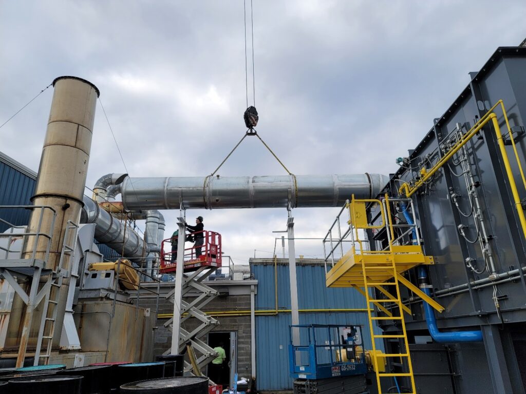 A picture of a large duct being lowered into place in a RTO system.