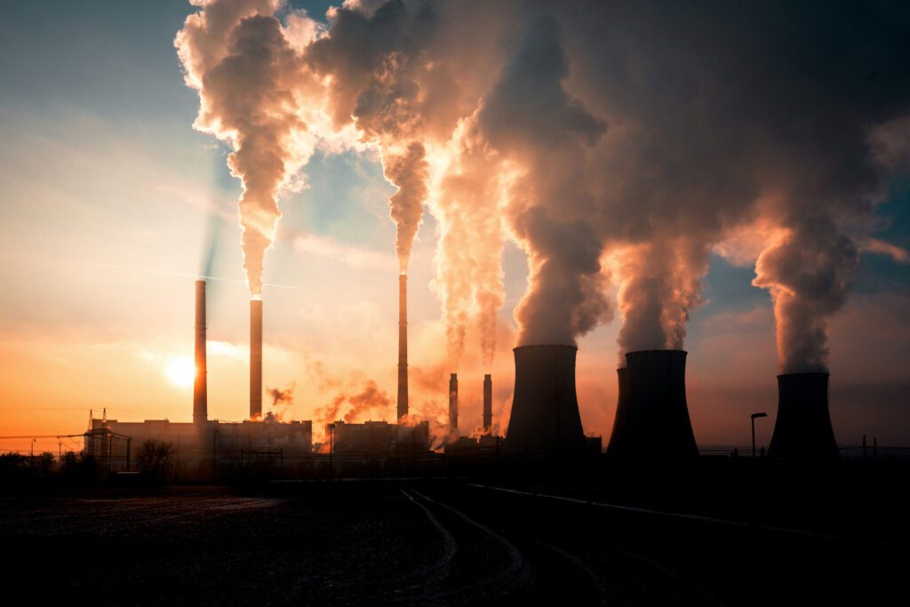 An image of different smoke stacks on the horizon of a sunset.