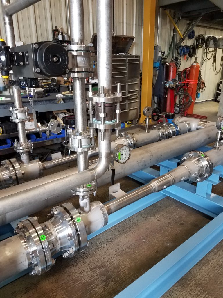 Detailed view of assembled stainless steel piping runs on the ozone injection skid, including fittings, gauges, and flow-control components at GSM Industrial