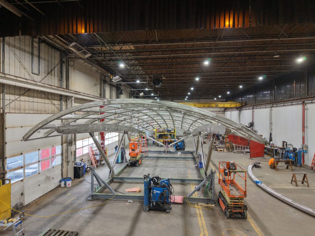 A massive T316 stainless steel architectural canopy under fabrication inside GSM Industrial’s shop, showing the contoured framework, weld preparation, and equipment used for the Washington, DC U-Street Station project.